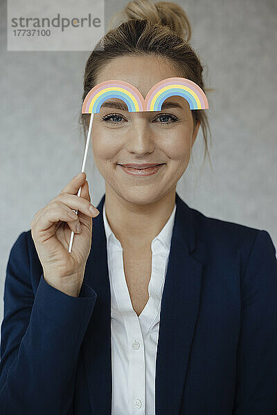 Lächelnde Geschäftsfrau mit Regenbogenstütze im Büro