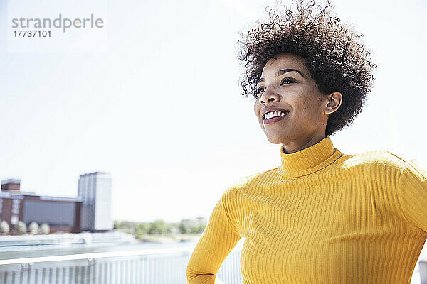 Lächelnde Frau mit Afro-Frisur an einem sonnigen Tag