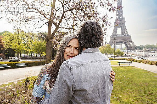 Lächelnde reife Frau umarmt ihren Freund vor dem Eiffelturm  Paris  Frankreich