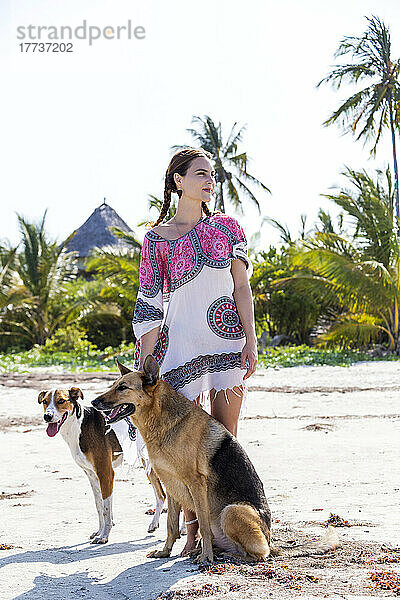 Nachdenkliche Frau von Hunden am Strand im Urlaub