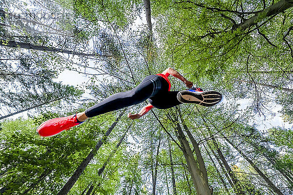 Aktive junge Frau joggt inmitten von Bäumen im Wald