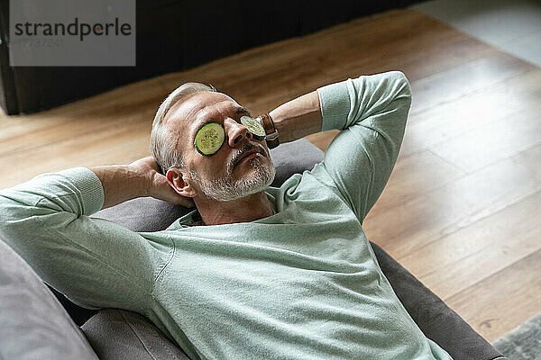 Mann entspannt sich zu Hause mit Gurkenscheiben auf den Augen