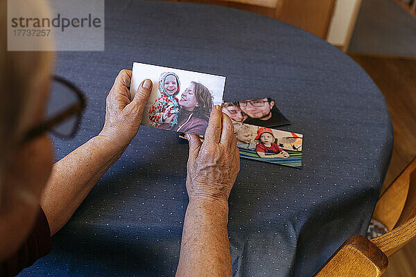 Einsame ältere Frau hält das Foto der Familie am Tisch