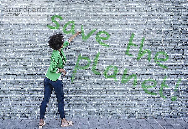 Junge Frau schreibt Save the Planet an die Wand