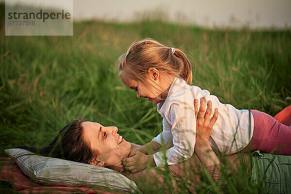 Lächelnde Mutter und Tochter liegen beim Picknick im Gras