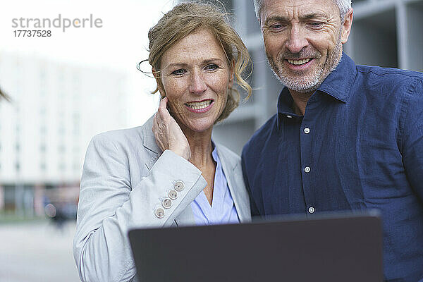 Lächelnde Geschäftsfrau mit Geschäftsmann  der Tablet-PC teilt