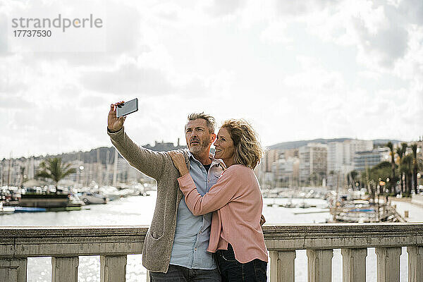 Reifer Mann macht im Urlaub ein Selfie mit Frau auf Smartphone