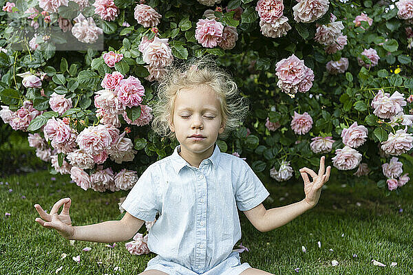 Mädchen mit geschlossenen Augen meditiert im Rosengarten