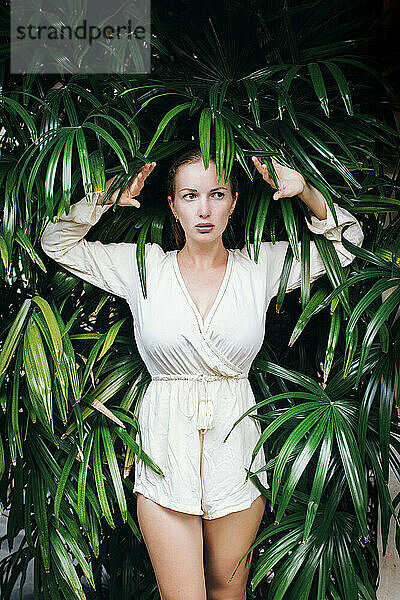 Portrait of young beautiful woman posing amid tropical plants