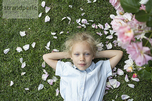 Nettes Mädchen mit geschlossenen Augen liegt auf Gras im Rosengarten