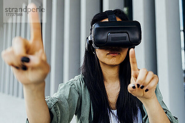 Junge Frau trägt VR-Simulator und zeigt