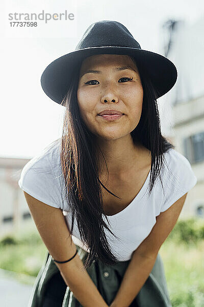 Lächelnde junge schöne Frau mit Hut an einem sonnigen Tag