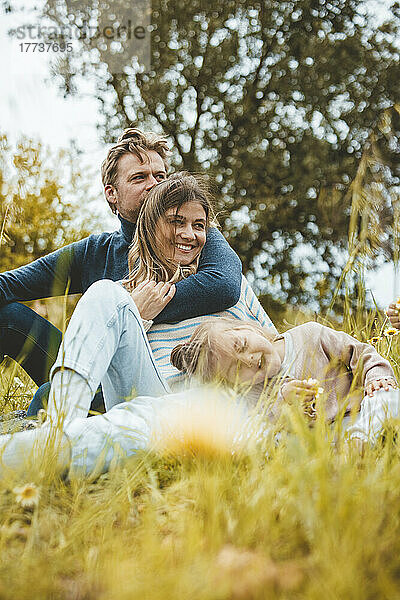 Happy mother and father with daughter in meadow