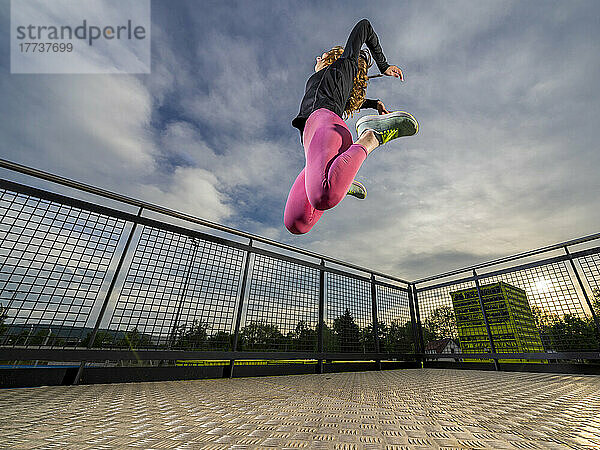 Young woman jumping in sports park at sunset