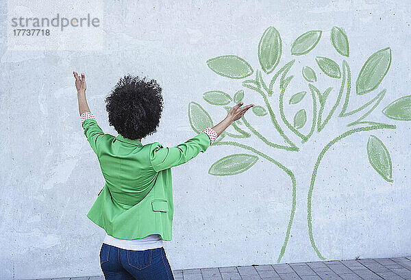 Woman presenting painted tree on wall