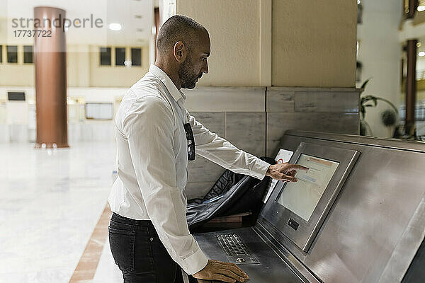 Mann benutzt Touchscreen-Computer und steht im Hotel