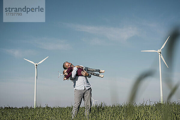 Glücklicher Mann mit Tochter steht an einem sonnigen Tag auf dem Feld
