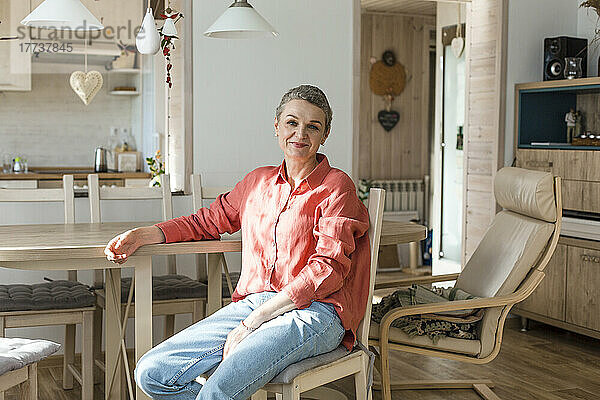 Frau sitzt zu Hause am Holztisch