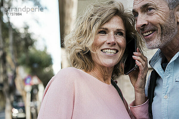 Glückliche Frau  die mit einem Mann am Smartphone spricht