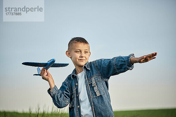 Junge hält Spielzeugflugzeug im Feld