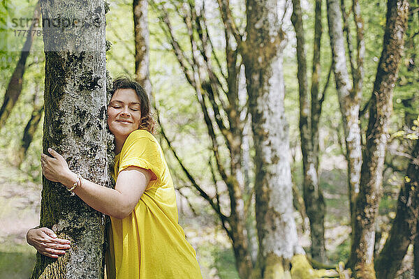 Frau umarmt Baum im Wald im Urlaub