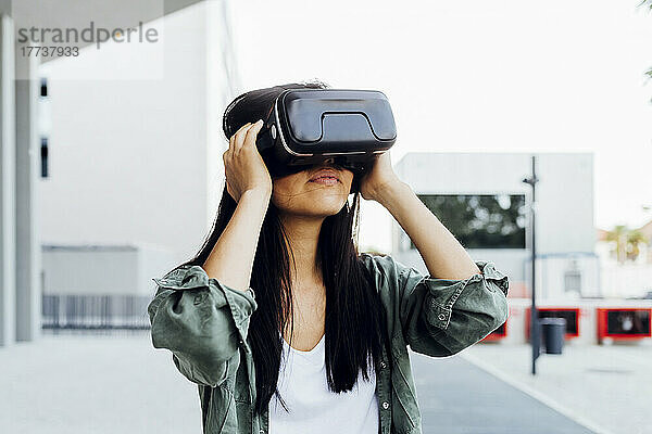 Junge Frau mit schwarzen Haaren trägt einen Virtual-Reality-Simulator