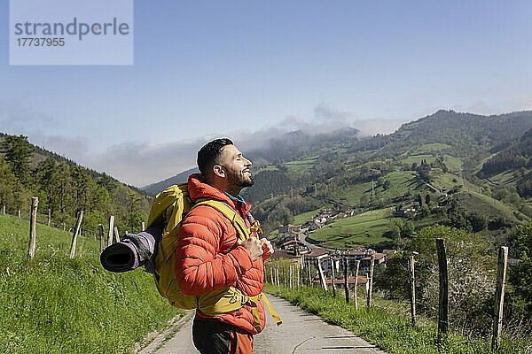 Lächelnder Wanderer mit Rucksack genießt sonnigen Tag