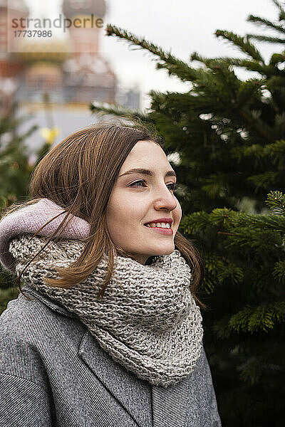 Lächelnde Frau mit Schal auf dem Weihnachtsmarkt