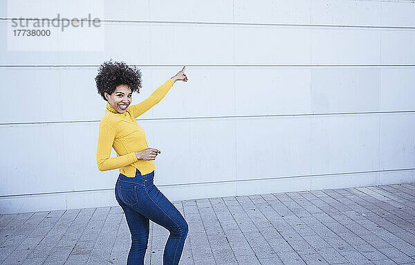 Smiling woman gesturing standing in front of wall
