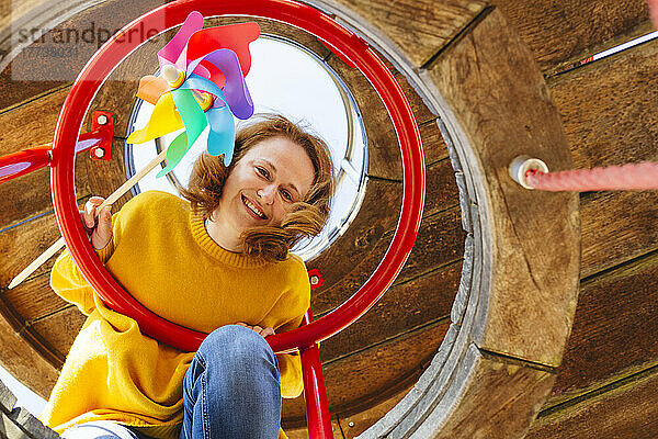 Glückliche Frau mit Windradspielzeug auf dem Spielplatz