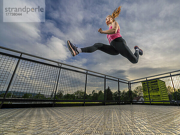 Active athlete jumping in sports park at sunset