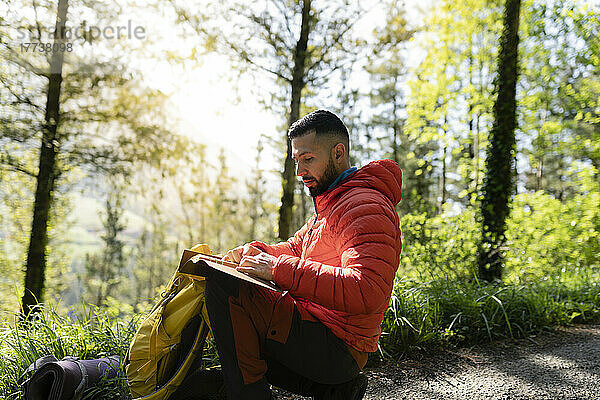 Mann liest Tagebuch und sitzt im Wald