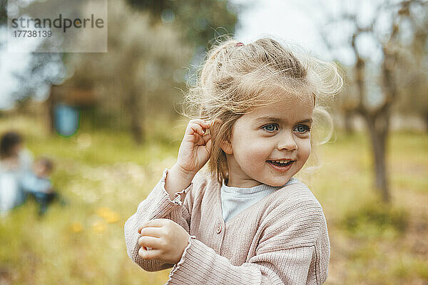Smiling cute blond girl standing in meadow