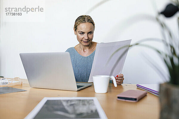 Geschäftsfrau analysiert Foto  sitzt zu Hause mit Laptop