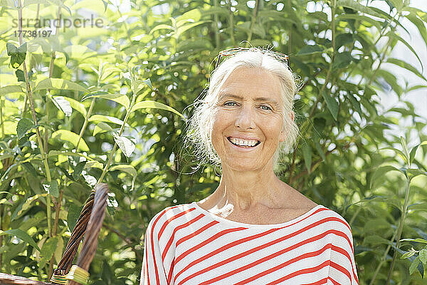 Glückliche reife Frau vor Pflanzen an einem sonnigen Tag