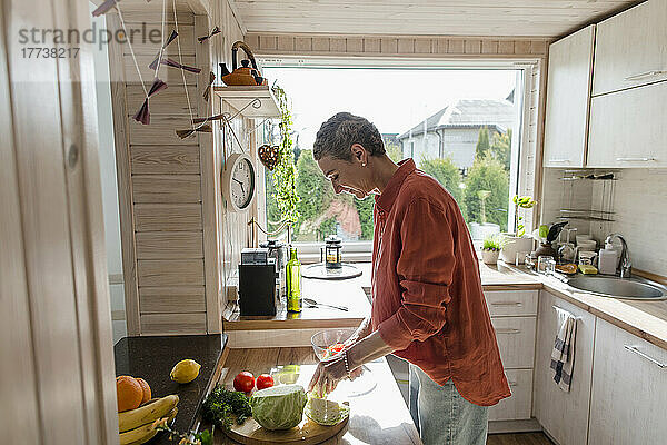 Frau bereitet zu Hause in der Küche Salat zu