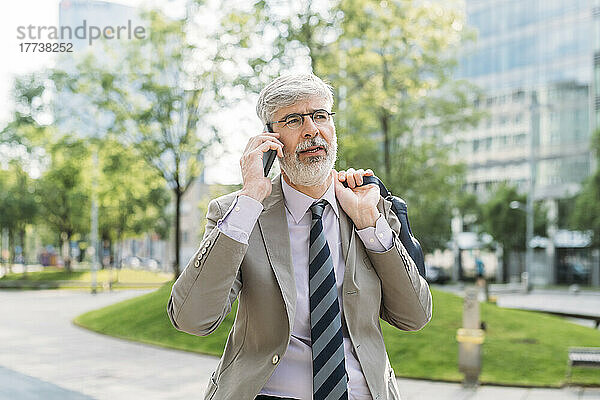 Geschäftsmann mit Brille spricht auf Smartphone