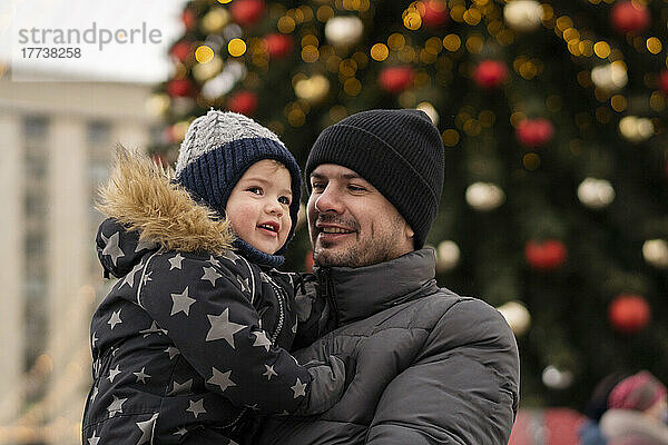 Lächelnder Mann mit Sohn auf dem Weihnachtsmarkt