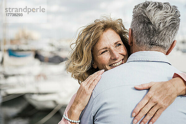 Smiling woman embracing man at harbor