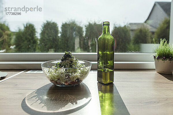 Salatschüssel und Flasche Olivenöl am Fenster