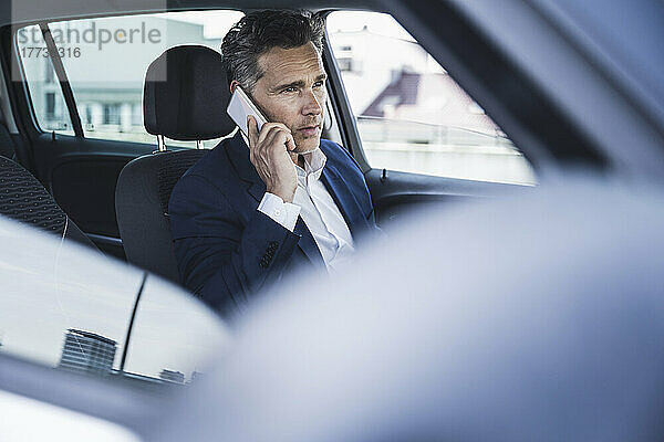 Reifer Geschäftsmann telefoniert auf dem Fahrersitz im Auto