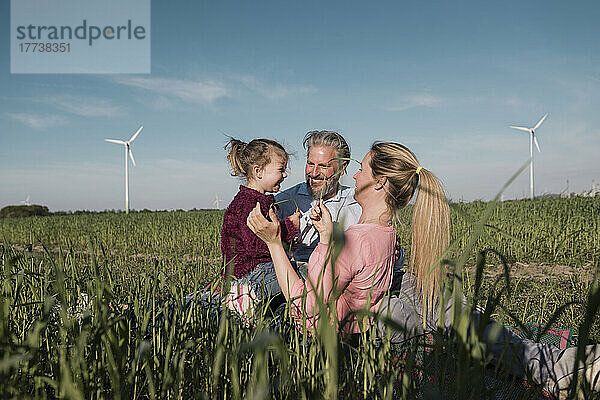 Glückliches Mädchen mit Eltern im Feld an einem sonnigen Tag
