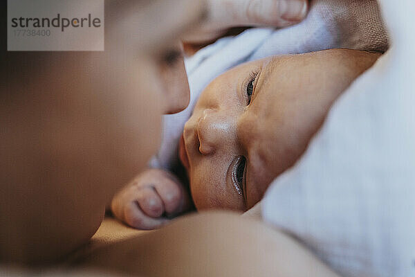 Mutter schaut auf das in ein Handtuch gewickelte Baby