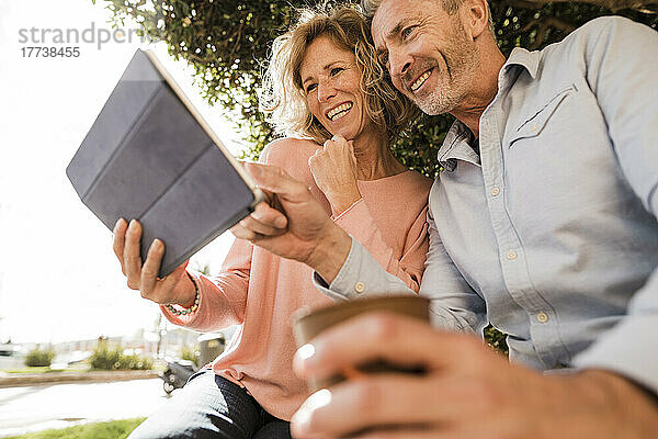 Glückliches älteres Paar benutzt Tablet-Computer im Park
