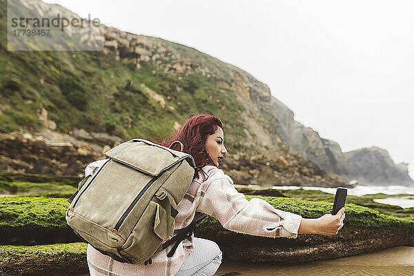 Frau mit Rucksack macht Selfie mit Smartphone