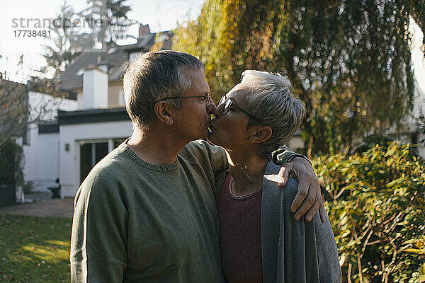 Zärtliches Seniorenpaar umarmt und küsst sich im Garten