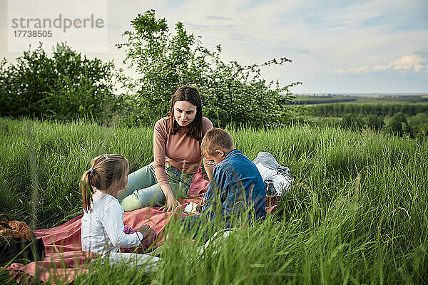 Mutter spricht mit Kindern beim Picknick im Feld