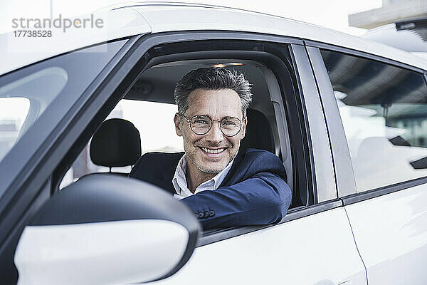 Glücklicher Geschäftsmann mit Brille sitzt im Auto