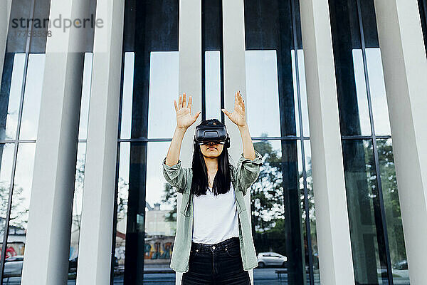 Junger Mann mit Virtual-Reality-Simulator gestikuliert vor der Säule