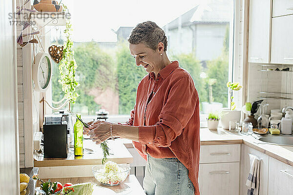 Frau hält Kräuter für Salat in der heimischen Küche